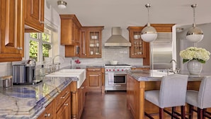 A kitchen with wooden cabinets, a stove, a sink, and a marble countertop. - Luxurious Boutique Villa w/ Private Pool, Hot Tub, EV Charger in Heart of Delray (Delray Beach)