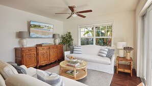 A living room with a white sofa, a wooden cabinet, a round coffee table, and a ceiling fan. - Luxurious Boutique Villa w/ Private Pool, Hot Tub, EV Charger in Heart of Delray (Delray Beach)