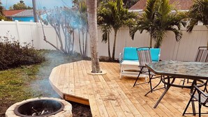 A wooden deck with a stone fire pit, outdoor furniture, and a view of a residential area. - BeachHouse Bungalow 🏝Spacious One Level Single Family  Home🏖Walk to the Beach! (Redington Beach)