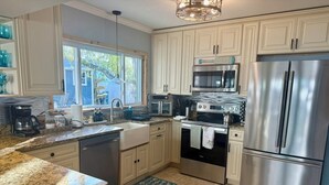 A kitchen with white cabinets, stainless steel appliances, a window, and a view of the outdoors. - BeachHouse Bungalow 🏝Spacious One Level Single Family  Home🏖Walk to the Beach! (Redington Beach)