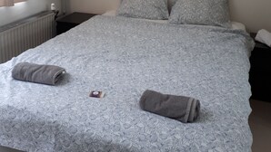 A bedroom with a bed, pillows, a rolled towel, and a small bedside table with a lamp. - Apartment in Rotterdam (Rotterdam)