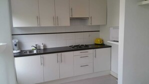 A modern kitchen with white cabinets, a black countertop, a gas stove, and a yellow appliance. - Apartment in Rotterdam (Rotterdam)