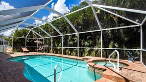 A swimming pool with a glass enclosure, surrounded by palm trees and a brick patio. - Villa Spain - Family Oasis in the Most Sought Area of Cape Coral (Cape Coral)