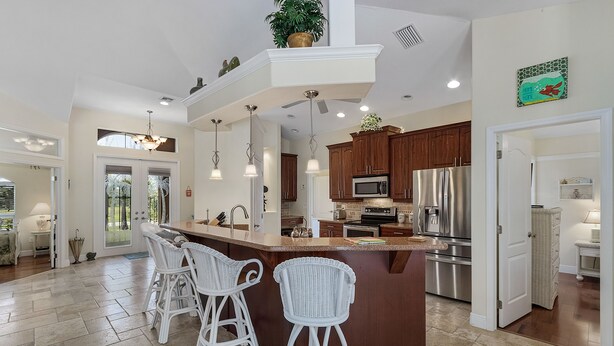 A spacious kitchen with a central island, white bar stools, and modern appliances. - Villa Spain - Family Oasis in the Most Sought Area of Cape Coral (Cape Coral)