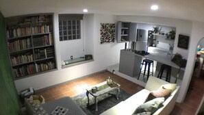 A living room with a sofa, a coffee table, and a bookshelf. There is a window and a kitchen area in the background. - Mexican Bohemian Loft (Queretaro)