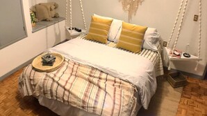 A bedroom with a bed, a bedside table, a hanging light fixture, and a small shelf with a teddy bear. - Mexican Bohemian Loft (Queretaro)