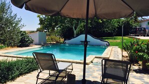 Une piscine avec deux chaises longues et un parasol.