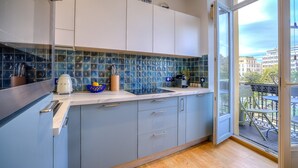 Eine moderne Küche mit grauen Schränken, einer blauen Küchenzeile und Blick auf die Stadt durch eine Glastür.