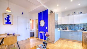 Eine moderne Küche mit blauen Schränken, einem Holzespeisetisch mit Stühlen und einer Wand in Blautönen.