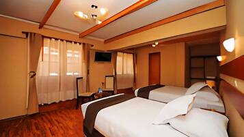 A hotel room with two beds, a television, and a wooden floor.