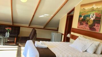 Una camera d'albergo con un letto, una scrivania, una sedia, un quadro e un soffitto con travi in legno.