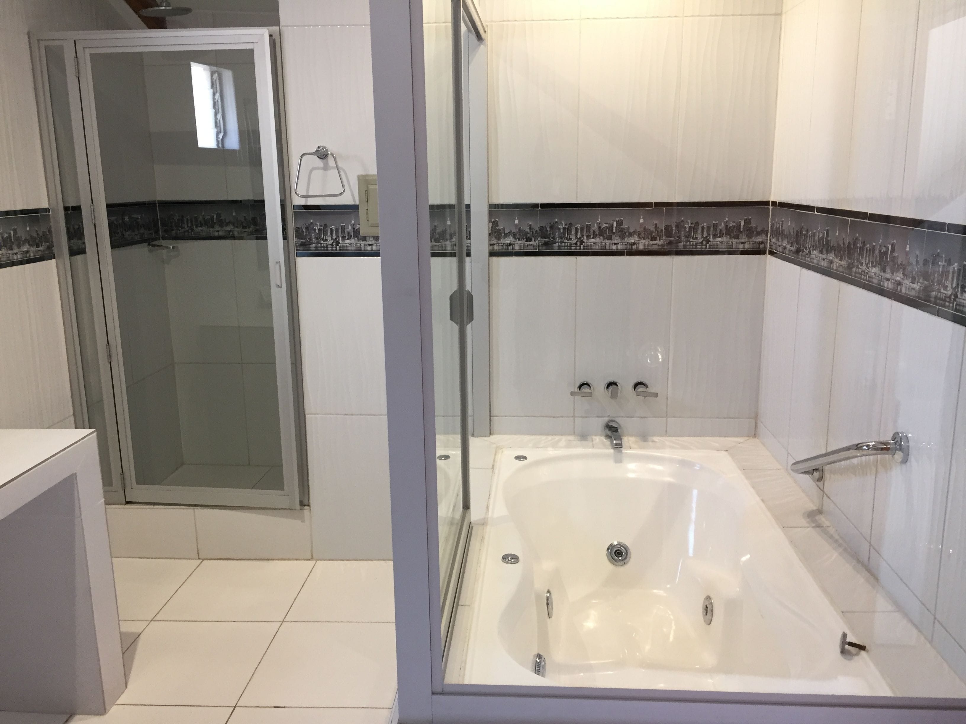 A modern bathroom with a glass-enclosed shower, a freestanding bathtub, and a tiled floor.