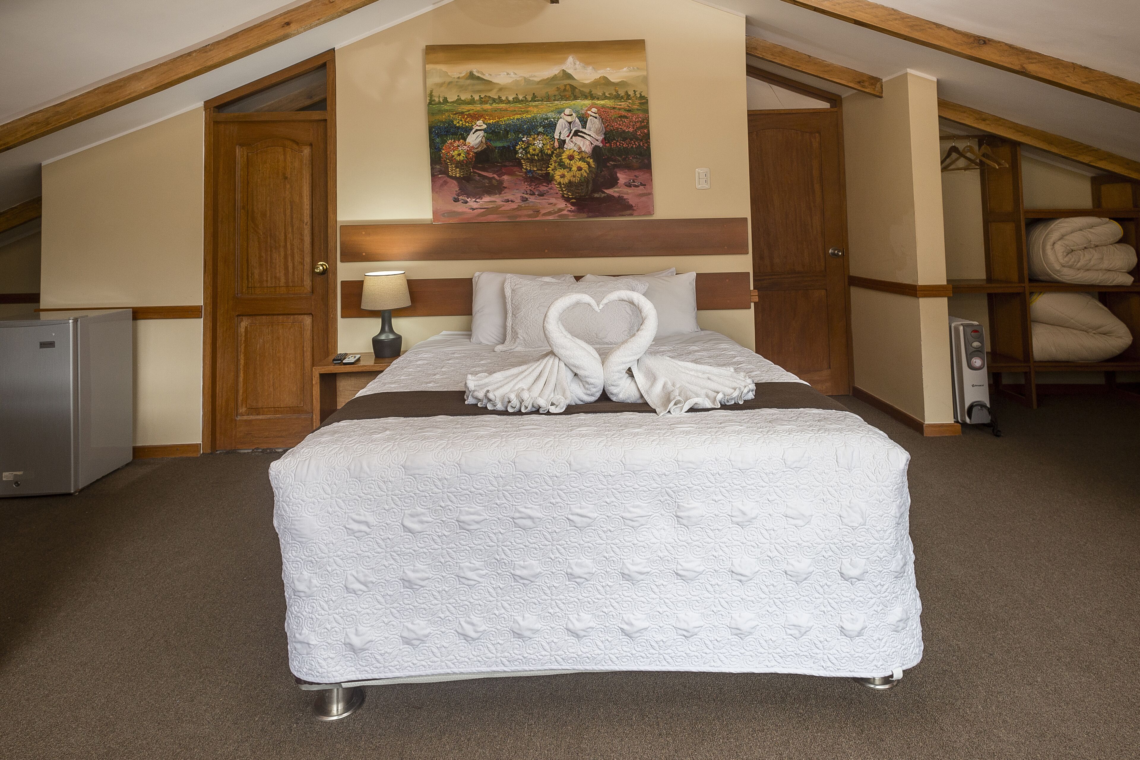 A bedroom with a large bed, a painting on the wall, and a wooden ceiling.