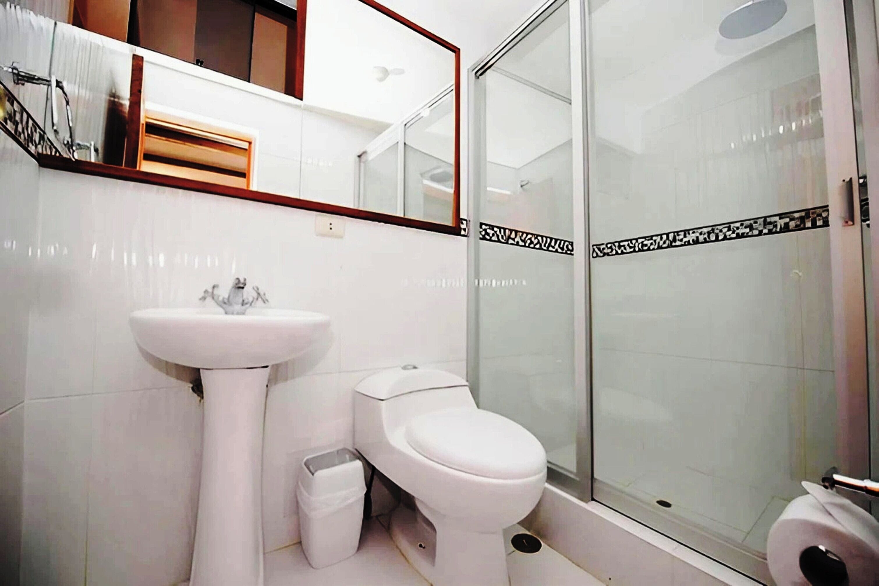 A bathroom with a white sink, toilet, and glass shower enclosure.