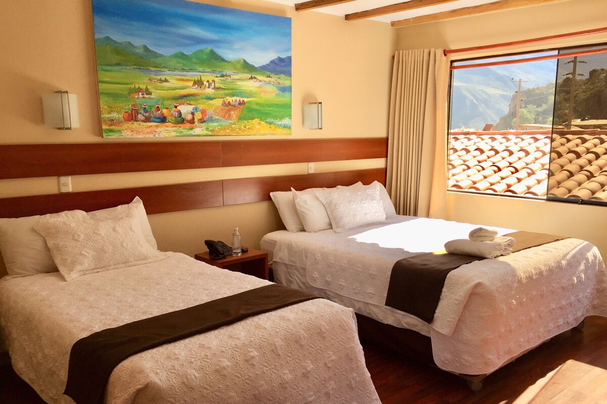A hotel room with two beds, a painting on the wall, a window with a view, and a wooden headboard.