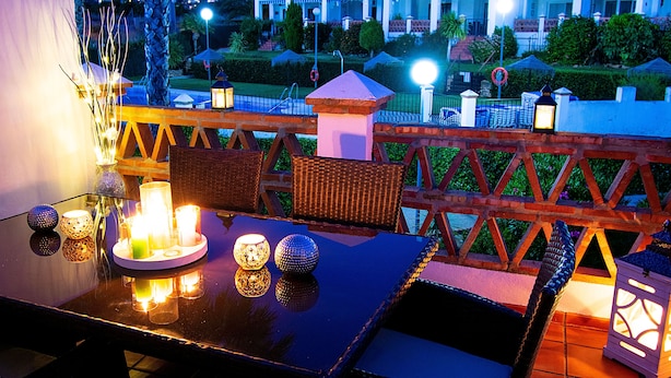 Een terras met eethoek, gedekt voor twee personen, met kaarsen en decoratieve accessoires.