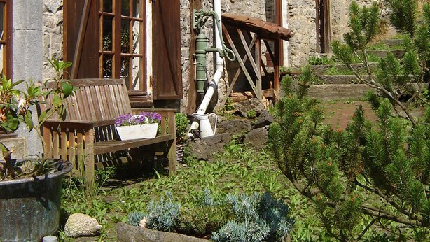 A stone building with wooden shutters, a bench, and a small garden area with plants and a rock. - cozy, comfortable, complete, spacious 6-person. holiday home with heated swimming pool (Hastière)