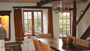 A dining area with a wooden table and woven chairs, a chandelier, and windows with curtains. - cozy, comfortable, complete, spacious 6-person. holiday home with heated swimming pool (Hastière)