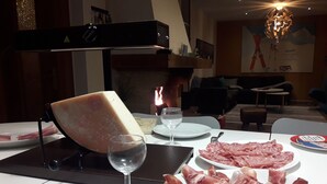 A dining table with plates of cured meats, a glass of water, and a cheese wheel. - Danish Chalet in Gérardmer (Gérardmer)