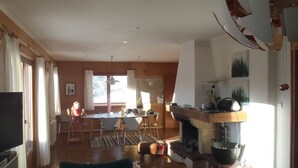 A spacious living room with a fireplace, a dining area, and a television. - Danish Chalet in Gérardmer (Gérardmer)