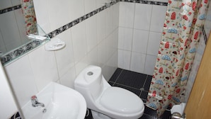 A bathroom with a toilet, sink, and shower curtain with a mushroom pattern. - Ruinas View (Ollantaytambo)