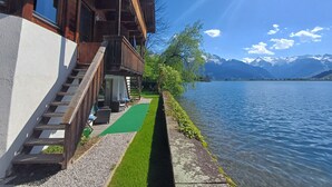 A wooden building with a balcony overlooking a lake and mountains. - Waterfront Apartment 1 (Zell am See)
