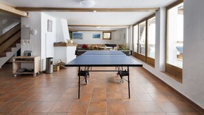 A spacious room with a ping pong table, a staircase, and large windows. - Waterfront Apartment 1 (Zell am See)