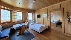 A wooden cabin with two beds, a seating area, and large windows offering a view of the outdoors. - Waterfront Apartment 1 (Zell am See)