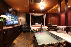 A modern hotel room with a large flat-screen TV, a glass coffee table, a comfortable sofa, and a bed with a canopy. - HOTEL GRASSINO URBAN RESORT UTSUNOMIYA - Adult Only (Utsunomiya)