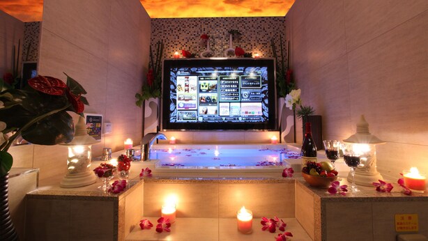 Un área de spa con menú digital, velas y flores.