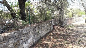 A stone wall with a narrow path leading through a wooded area. - Maison Grenat.  Vacation home with private pool, (Orgnac-l'Aven)