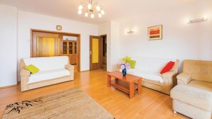 Ein Wohnzimmer mit zwei Sofas, einem Couchtisch, einem Holzkabinett und einer Kristallleuchtre.