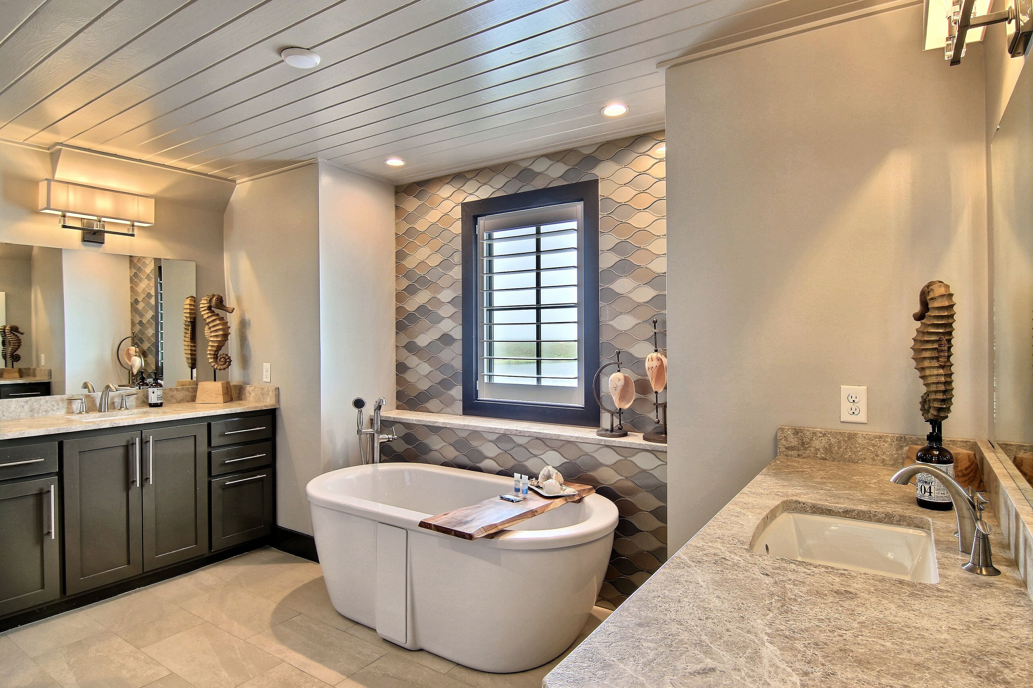 A modern bathroom with a freestanding bathtub, a vanity with a sink, and a window above the bathtub.