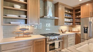 A modern kitchen with wooden cabinets, a stainless steel stove, and a built-in oven. - The Luxe Lookout - Private Pool & Breathtaking Beach Views (Port Aransas)