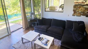 A modern living room with a dark grey sofa, a white coffee table, and a large mirror on the wall. - 2025 Updates - Modern Townhome In Deer Valley With Shuttle Service (Park City)
