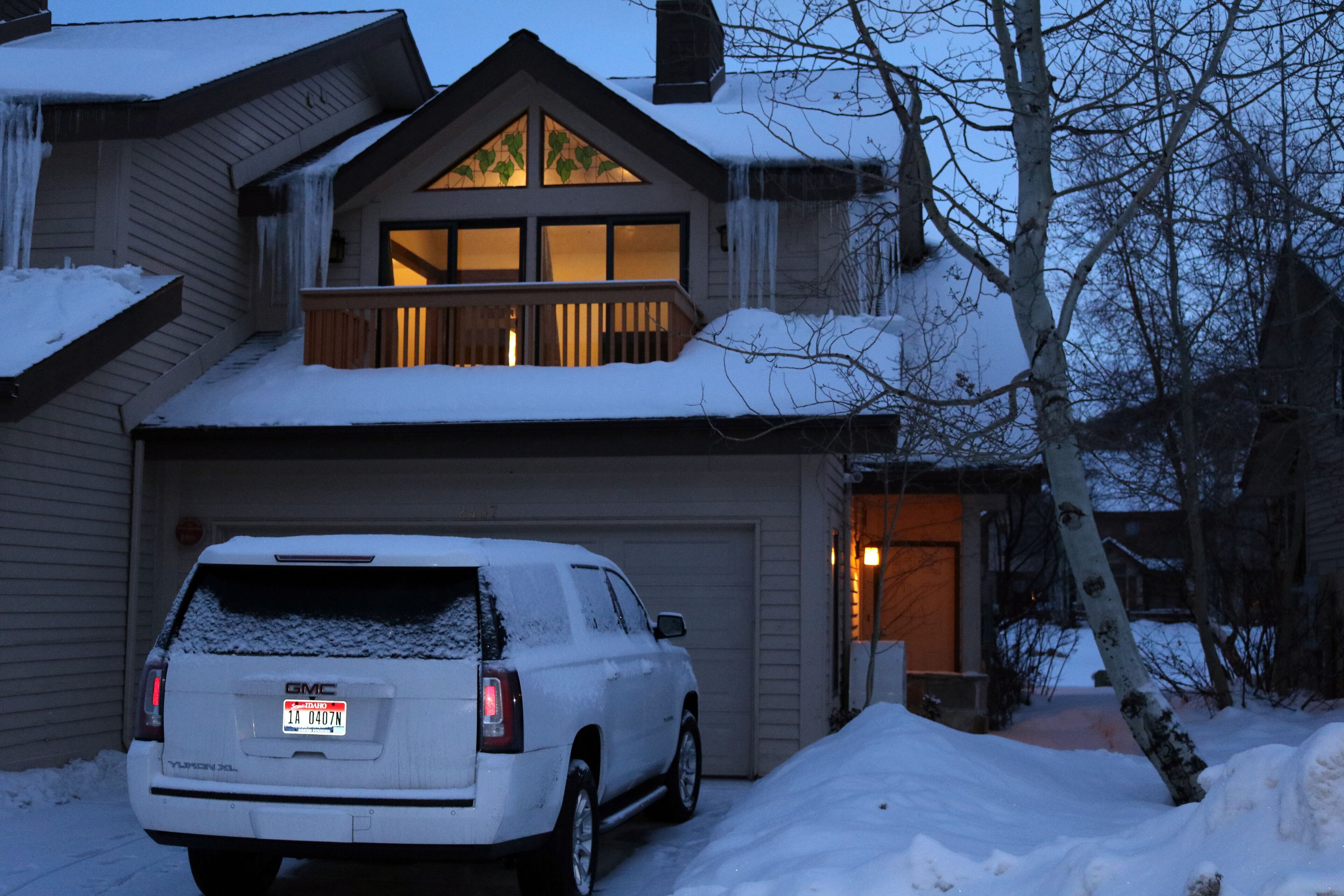 A house with a garage, a covered driveway, and a snow-covered landscape.
