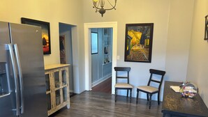 A kitchen with a refrigerator, wooden cabinet, two chairs, and a table with a glass bowl. - Downtown Historic Charm with Modern Comfort (Prescott)