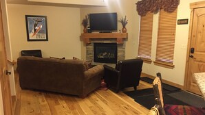 Una sala de estar con chimenea, televisor y un cartel en la pared.