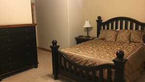 Un dormitorio con cama, cómoda, mesita de noche y lámpara.
