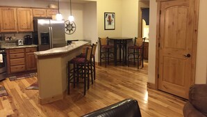 Una cocina amplia con armarios de madera, un refrigerador de acero inoxidable y una barra con taburetes.