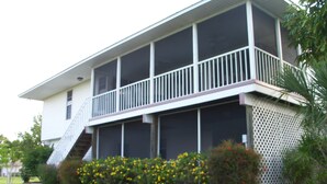 Une maison à deux étages dotée d’un porche couvert et d’un balcon grillagé.