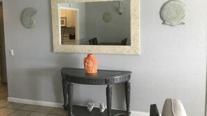 A room with a large mirror on the wall, a small table with a vase, and decorative shells. - Property 1156542    "Blue Waters Beach Front Villa in Paradise"  (St Thomas)