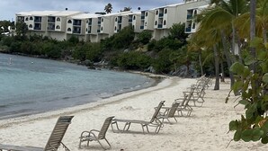 A beach with rows of sun loungers and a building with balconies in the background. - Property 1156542    "Blue Waters Beach Front Villa in Paradise"  (St Thomas)