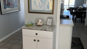 A kitchen with a white countertop, a framed abstract painting, and a small bowl of decorative items. - Property 1156542    "Blue Waters Beach Front Villa in Paradise"  (St Thomas)