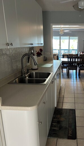 A kitchen with a stainless steel sink, white cabinets, and a dining area with a table and chairs.