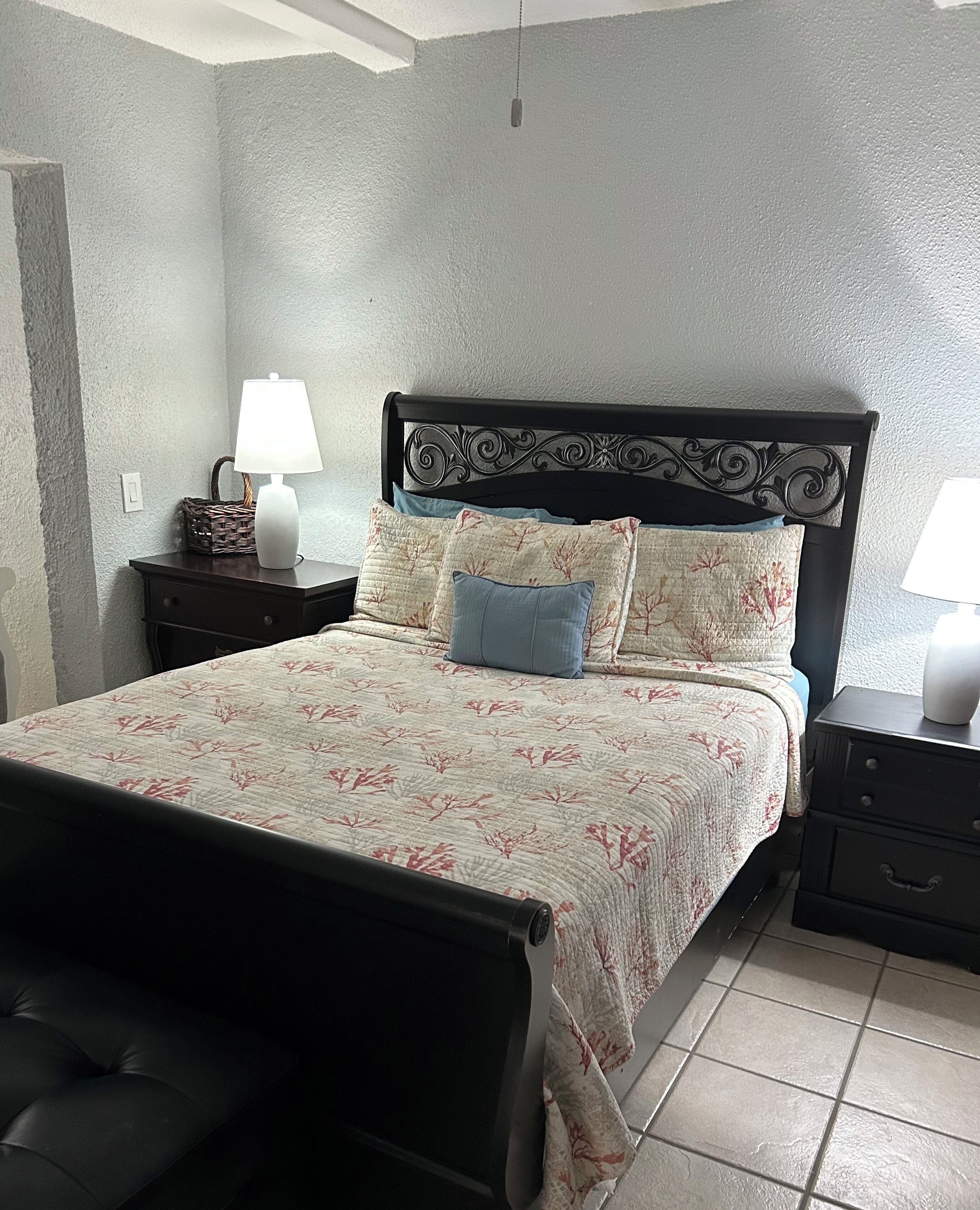 A bedroom with a bed, nightstands, lamps, and a headboard with decorative patterns.
