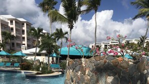 A clear swimming pool with a stone wall and palm trees. - Property 1156542    "Blue Waters Beach Front Villa in Paradise"  (St Thomas)