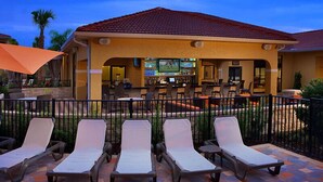 A covered outdoor area with lounge chairs and a bar.