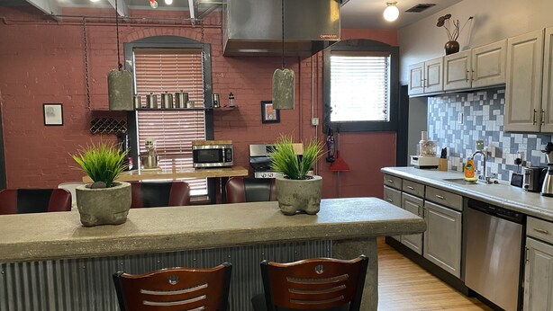 A modern kitchen with a central island, two bar stools, a microwave, a stove, and a sink. - Unique two bedroom house in a great location in Colorado springs.   (Colorado Springs)