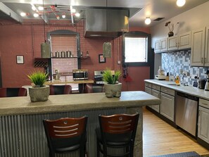 A modern kitchen with a central island, two bar stools, a microwave, a stove, and a sink. - Unique two bedroom house in a great location in Colorado springs.   (Colorado Springs)